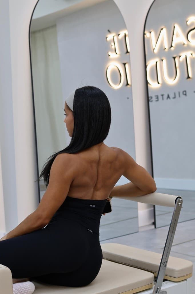 Client seated on a reformer in front of the Santé Studio mirror